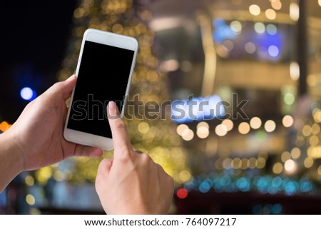 Smartphone on hand with bokeh night street city.