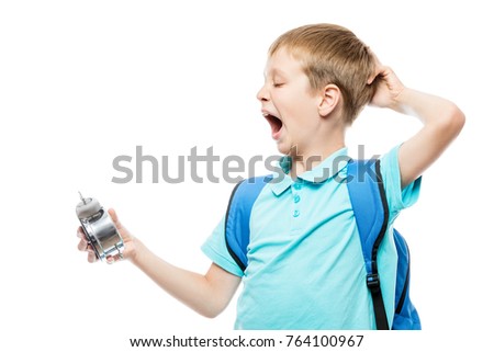 tired yawning schoolboy with an alarm clock on white background