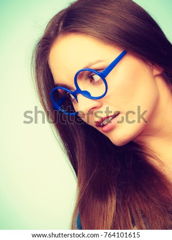 Studying, beauty of education and fun concept. Attractive nerdy woman in weird big glasses. Studio shot on blue background