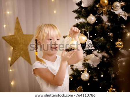 little girl with Christmas ball near Christmas tree