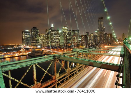 View of downtown Manhattan from the Brooklyn Bridge with traffic flying by.