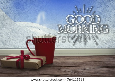 Beautiful image of a red cup and gift on a window sill with a beautiful winter landscape outside the window.