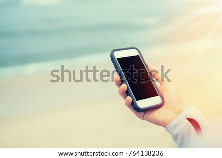 Copy space of woman hand using smart phone at beach abstract background. Travel adventure and business summer holiday concept. Shallow depth of field. Vintage tone filter effect color style.