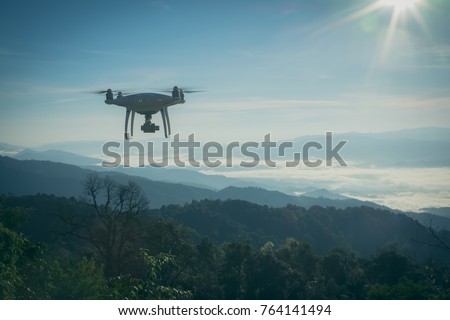 UAV drone copter flying with digital camera.Drone with high resolution digital camera. Flying camera take a photo and video.The drone with professional camera takes pictures of the misty mountains.

