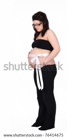 beautiful pregnant standing looking down at the white satin ribbon tied around her bare belly. isolated