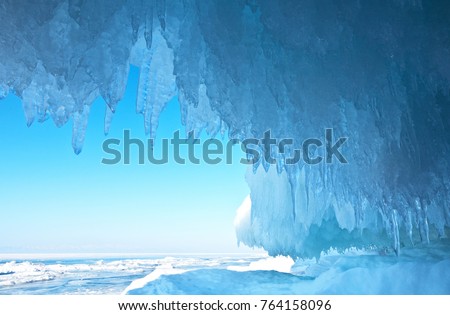 Baikal Lake. Thick blue ice and icicles on the coastal rocks of Olkhon Island in winter. Natural cold background Royalty-Free Stock Photo #764158096