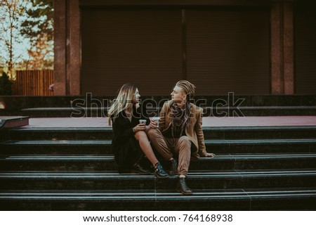 Beautiful young couple sitting outside and talk to each other. Couple enjoying morning coffee. Lovely happy couple. Picture of romantic couple dating.