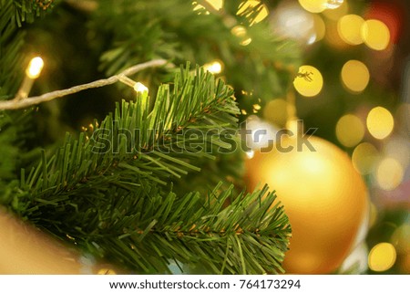 Closeup pine leaves and golden Christmas balls Decorated on Pine Tree on Christmas night with blurry background and bokeh of Christmas lighting. 