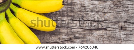 BANNER, Long Format Bunch of raw ripe organic yellow bananas on wooden background.