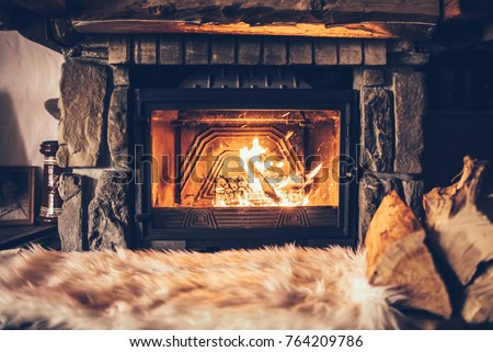 Warm cozy fireplace with real wood burning in it. Cozy winter concept. Christmas and travel background with space for your text.