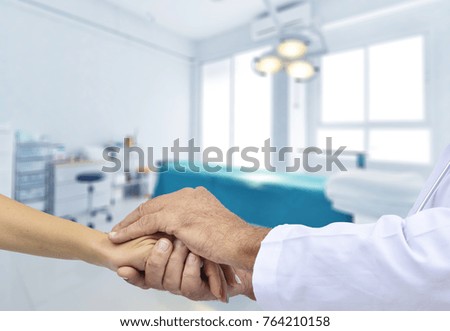 Friendly male doctor's hands holding female hand for encouragement and empathy. Trust cheering and support ,medical ethics concept. operating room background