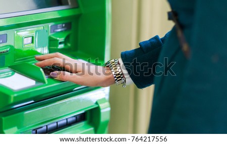 Image of woman in coat at green cash machine