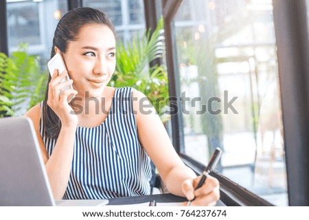 Business woman talking on the phone and writing on a note pad in the office.