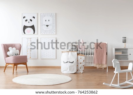 White rocking horse and carpet in child's room with pink armchair, paper bags, drawings and bed Royalty-Free Stock Photo #764253862