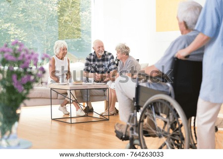 Group of elderly people sitting on the sofa during lunch time in common room Royalty-Free Stock Photo #764263033