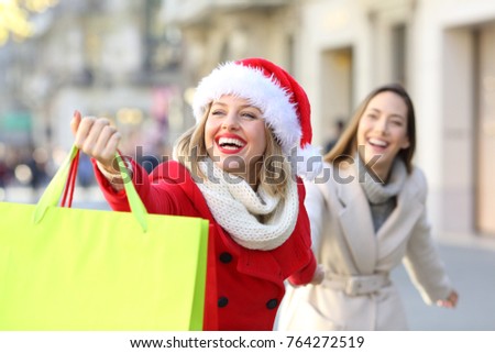 Shoppers wearing santa claus hat shopping and showing bags in christmas outdoor on the street