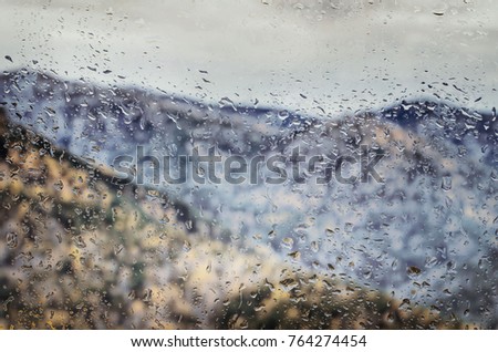 Autumn mountain landscape behind a glass with drops of water. 