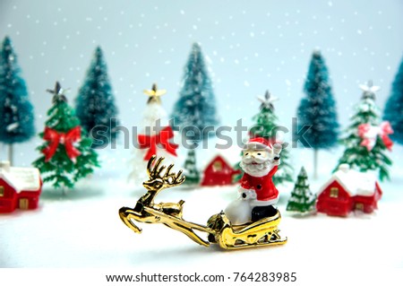 Green and white christmas tree with Santa and reindeer with snow. They are toy.