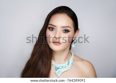 Close-up portrait of beautiful girl pretty lady with professional makeup, arrows long lashes, wavy hair styling. Luxury New Bright color make-up shiny lipstick glossy cosmetics. photo conceptual idea