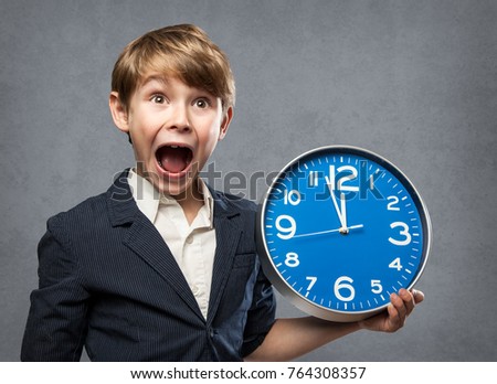 Happy Surprised 7 Year old Boy, Holding a blue Big Clock, just minutes before midnight: either, he is warning us that time is running out, or ready to celebrate New Year