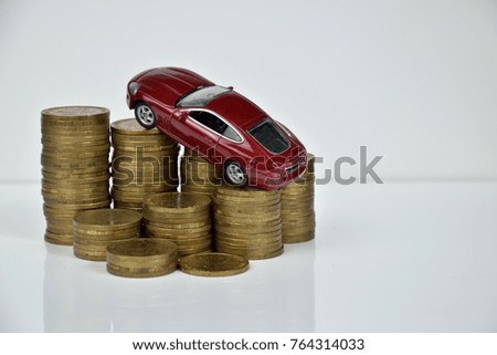 red car model and stacks of coins on white background