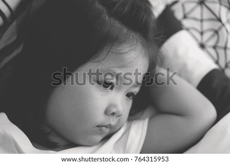 child asian girl sleepy and watching TV on sofa bed in living room.Asian child.Child development.black and white tone.