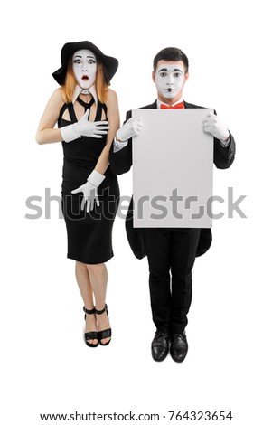 Couple of mimes on white. Woman is shocked, man is holding a blank placard, space to insert your text or picture. Studio shot.