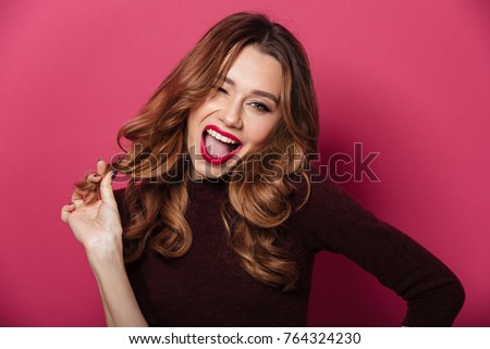 Photo of happy young beautiful woman standing isolated over pink background. Looking camera.