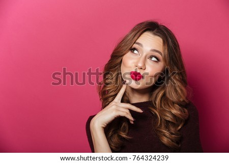 Image of young beautiful woman standing isolated over pink background. Looking aside.