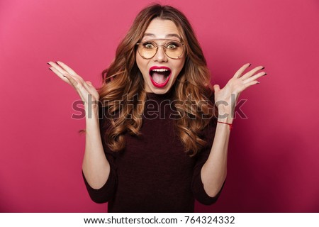Image of young surprised lady wearing glasses standing isolated over pink background. Looking camera.