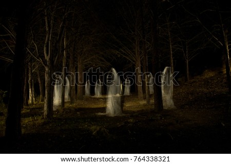 Picture of a group of ghosts in the middle of the forest with total darkness and made with the lightpainting technique