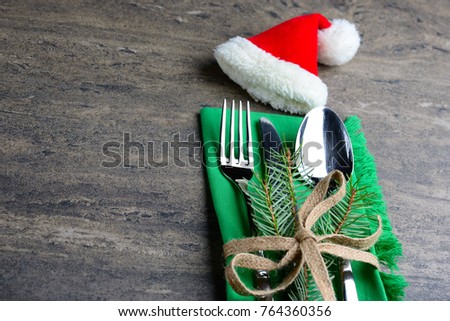 Festive cutlery set: knife, spoon and fork with ribbon and green cloth decorated with a sprig of pine. New Year and Christmas holiday table setting. Creative dark background with a copy space.