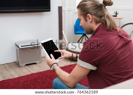 man sitting on sofa while using digital tablet  