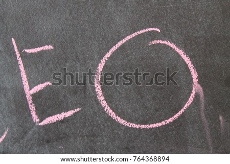 Pink letters on a dark background. Jumbled arrangement of different sized writen with chalk letters of the alphabet. Colour raised Latin letters in perspective.