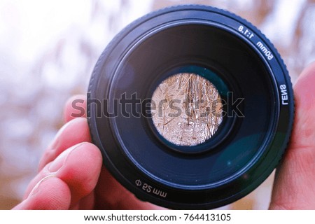lens in hand against nature background. highlights.