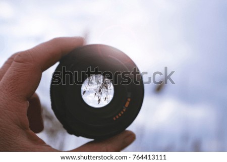 lens in hand against nature background. highlights.