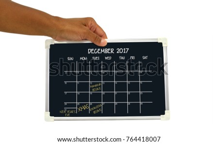 December 2017 Calendar Blackboard with Hanukkah, Christmas, Kwanzaa and New Year's Eve written in held by hand white background