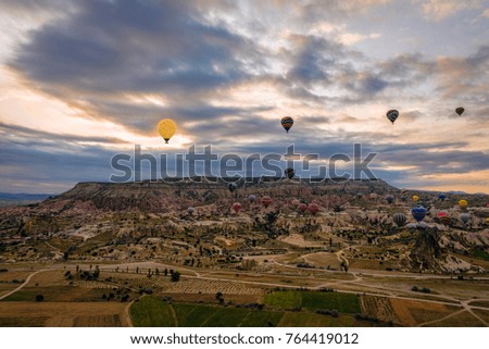 Family of fairy chimneys in Cappadocia under cloudy early morning skies with hot air balloons in the distance