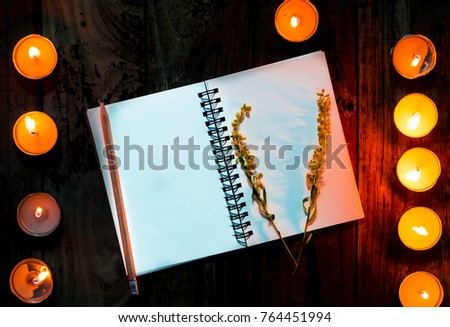 The diary is placed on a wooden table decorated with candles and decorated with small flowers. Make it more beautiful in the dark and have space on paper for text input.
