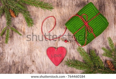 Christmas background with fir tree and knitted gift. Preparing for Christmas. Red heart pendant.