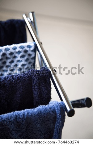 Overhead close up on freshly washed and wet blue towels hanging on a chrome metal drying rack, with white background