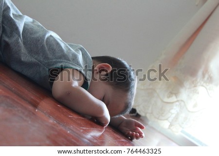 a little boy laying down on the wooden floor background