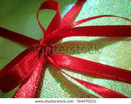 Background and texture of red ribbon that tied in bow style on light green wrapping paper for a gift or present