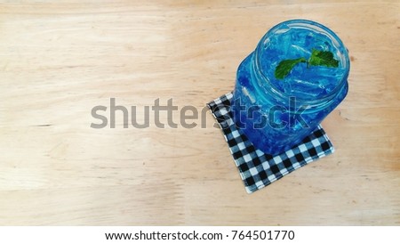 Fresh Blue Hawaii soda with mint leaves on the wooden table and left copy space. Top view of cocktail drink.  