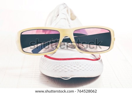 A funny picture on which an old white sneaker is depicted in a hipster sunglasses