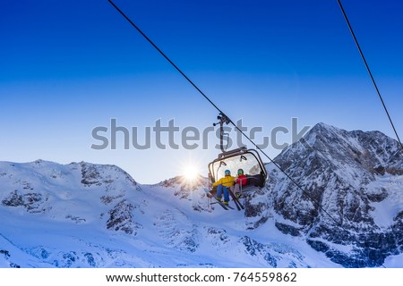 Happy family enjoying winter vacations in mountains. Father with teenage daughter going up with ski lift in Solda, South Tirol, Italy