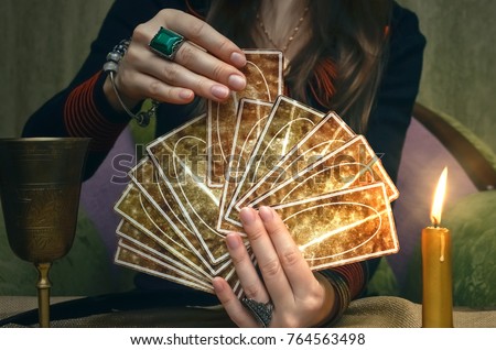 Tarot cards on fortune teller desk table. Future reading. Woman fortune teller holding and hands a deck of tarot cards and shuffles it. Royalty-Free Stock Photo #764563498