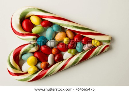 Heart shaped Christmas candy canes and colorful candies on white background