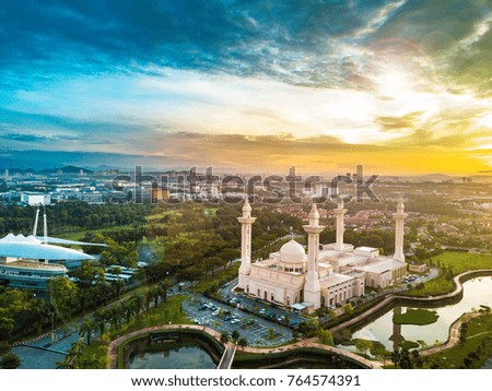 Aerial view of mosque during sunrise with sun flare.