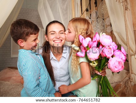 Children congratulate mother give her a bouquet of flowers and a kiss, happy mother's family day